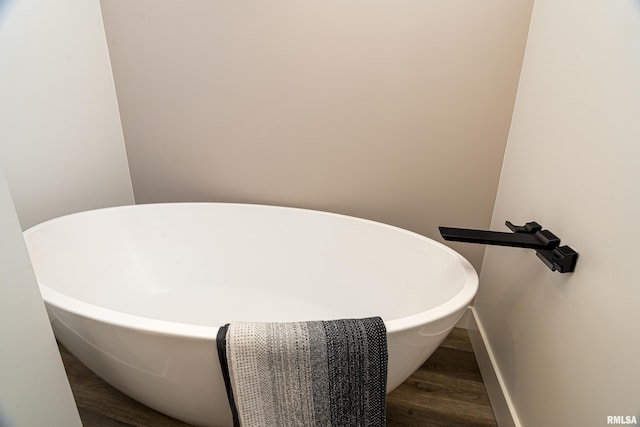 room details featuring a tub to relax in and wood-type flooring