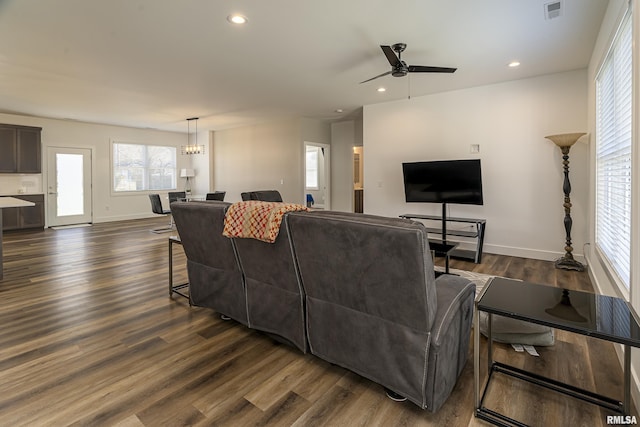 living room featuring dark wood-type flooring and ceiling fan with notable chandelier