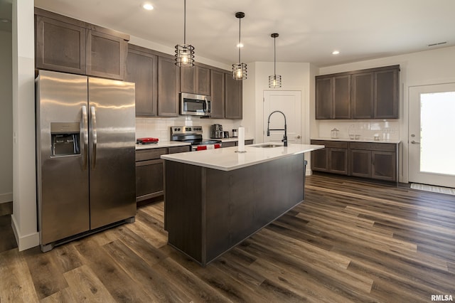 kitchen with pendant lighting, a center island with sink, sink, dark hardwood / wood-style floors, and appliances with stainless steel finishes