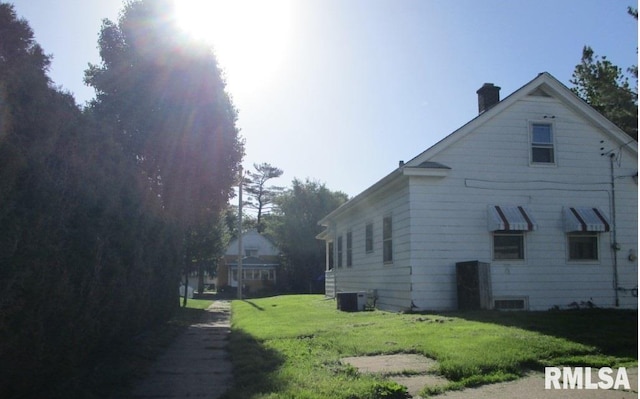 view of side of property featuring a yard and central air condition unit