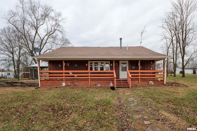 view of front of property featuring roof with shingles, board and batten siding, covered porch, and a front yard