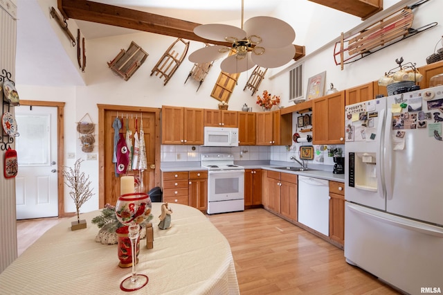 kitchen with tasteful backsplash, light countertops, light wood-style floors, white appliances, and high vaulted ceiling