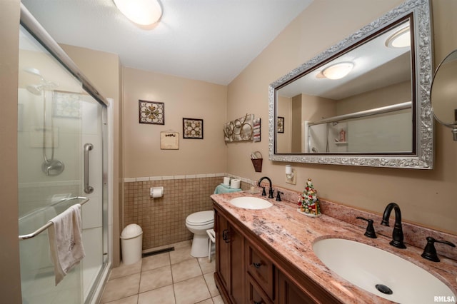 bathroom with tile walls, a stall shower, tile patterned floors, and a sink