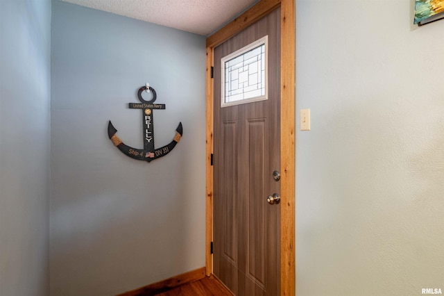 entrance foyer featuring dark wood-type flooring, baseboards, and a textured ceiling