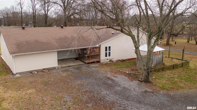 exterior space featuring a shingled roof, fence, and dirt driveway