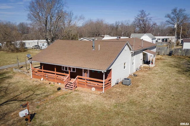 view of front of house with a deck, central AC unit, a front yard, and roof with shingles