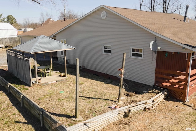 exterior space with a patio, a lawn, and roof with shingles