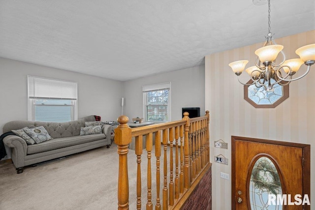 carpeted entrance foyer featuring an inviting chandelier and a healthy amount of sunlight