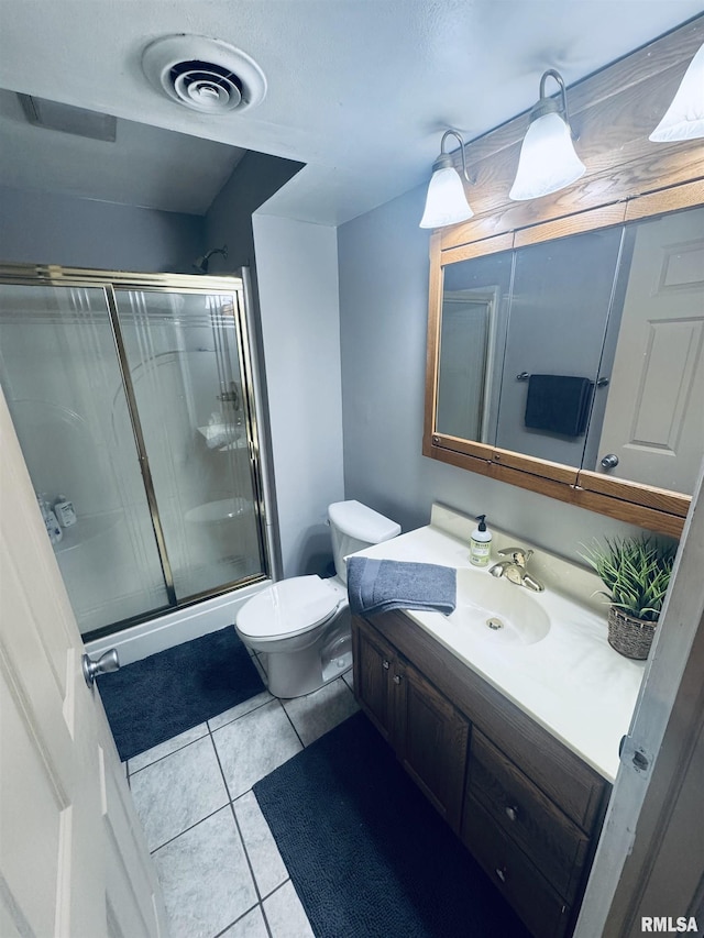 bathroom featuring toilet, a shower with door, vanity, and tile patterned floors