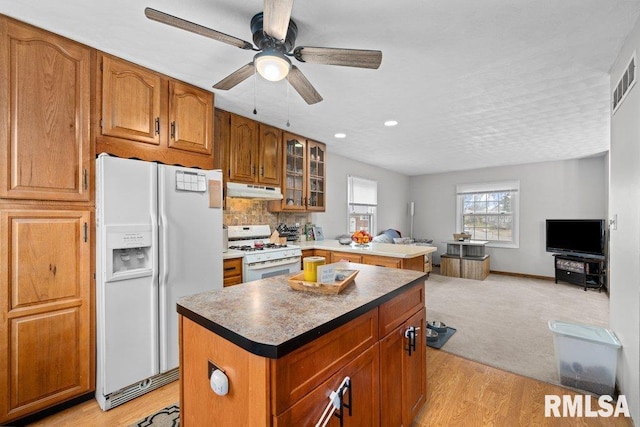 kitchen with white appliances, tasteful backsplash, light hardwood / wood-style flooring, and a kitchen island