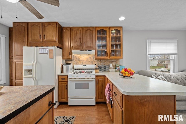 kitchen featuring white appliances, light wood-type flooring, ceiling fan, and backsplash