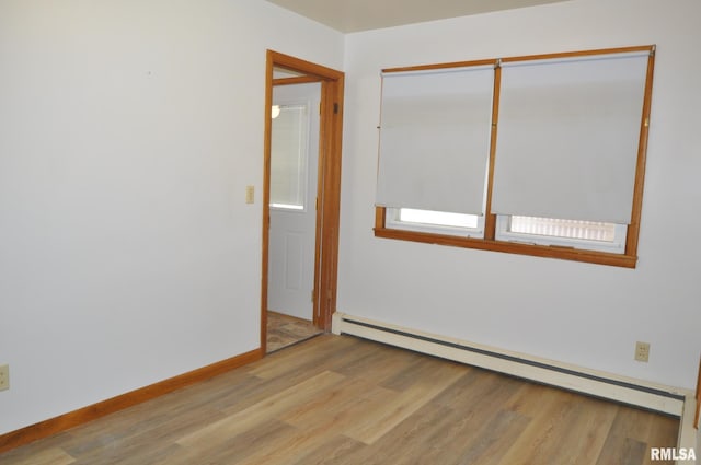 spare room featuring baseboard heating and light wood-type flooring