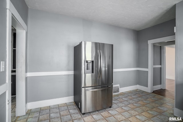 kitchen featuring a textured ceiling and stainless steel refrigerator with ice dispenser