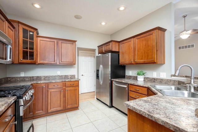 kitchen with appliances with stainless steel finishes, light tile patterned floors, ceiling fan, and sink