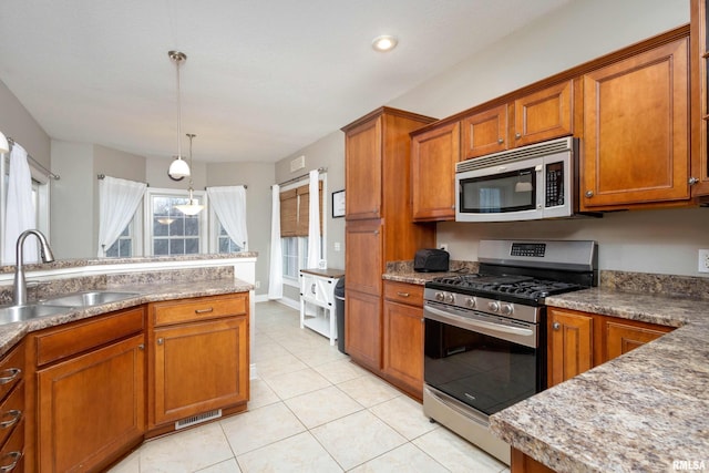 kitchen with pendant lighting, light tile patterned flooring, sink, and appliances with stainless steel finishes