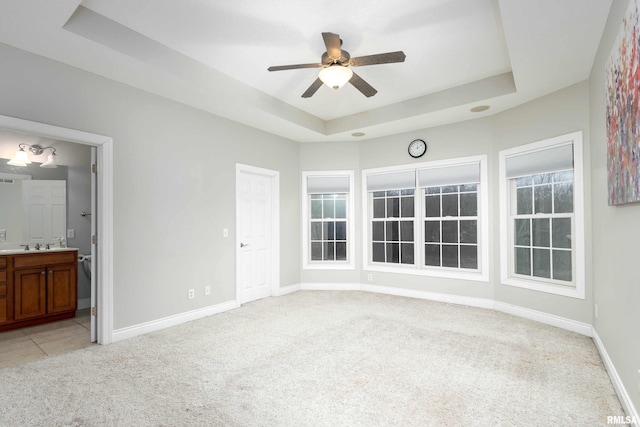 empty room featuring light colored carpet, a raised ceiling, and ceiling fan