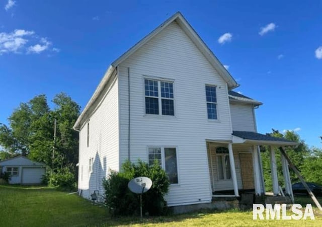 back of property featuring covered porch and a yard