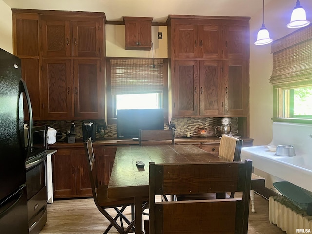 kitchen featuring decorative backsplash, a wealth of natural light, hanging light fixtures, and black appliances