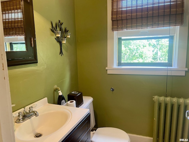 bathroom featuring a wealth of natural light, toilet, vanity, and radiator