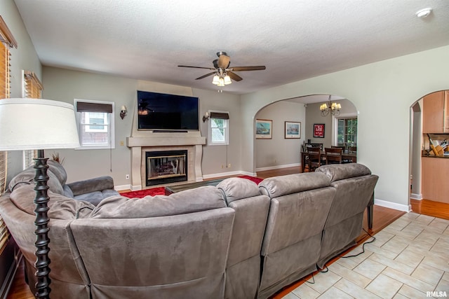 living room featuring ceiling fan with notable chandelier and a textured ceiling