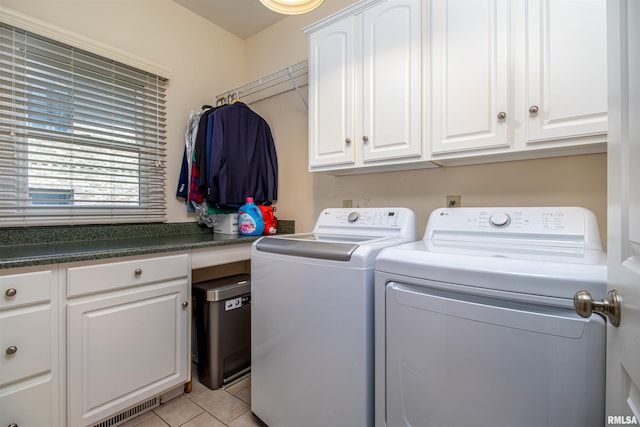 laundry area featuring cabinets, light tile patterned floors, and washing machine and dryer