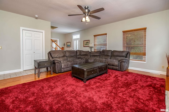 living room featuring ceiling fan, light hardwood / wood-style flooring, and a textured ceiling