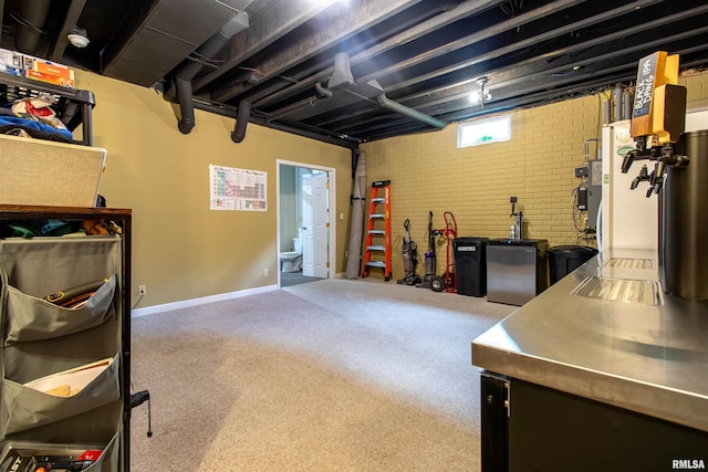 basement featuring brick wall and fridge