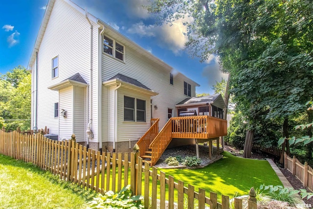 rear view of house featuring a wooden deck, a sunroom, and a yard