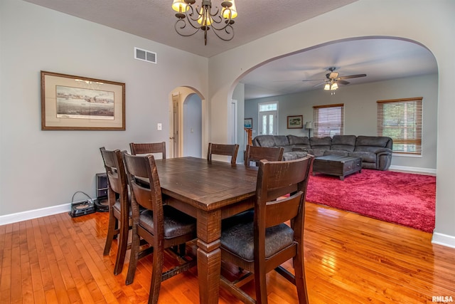 dining space with a textured ceiling, ceiling fan with notable chandelier, and light hardwood / wood-style floors