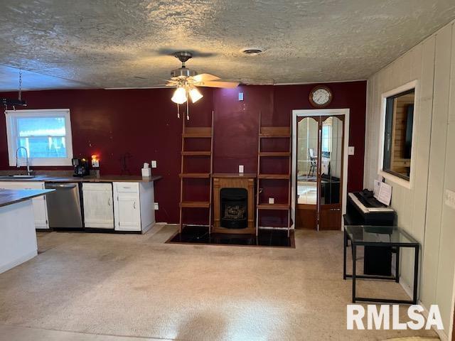 carpeted living room with a textured ceiling, ceiling fan, and sink