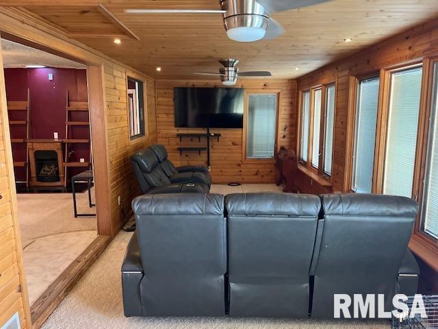 living room featuring carpet, wooden walls, ceiling fan, and wooden ceiling