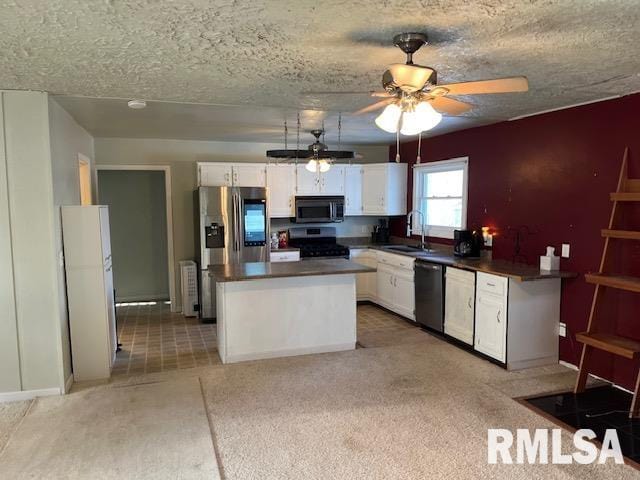 kitchen featuring white cabinetry, sink, ceiling fan, stainless steel appliances, and a kitchen island