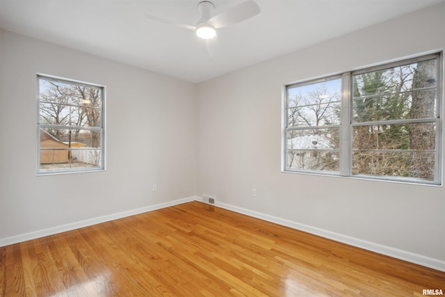 empty room featuring ceiling fan, light hardwood / wood-style floors, and a wealth of natural light