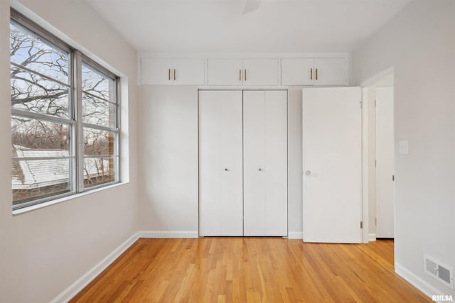 unfurnished bedroom with multiple windows, a closet, and light hardwood / wood-style flooring