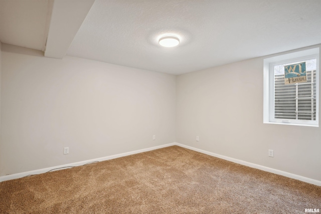 carpeted empty room with beamed ceiling and a textured ceiling