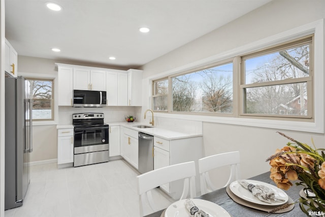 kitchen with sink, white cabinets, decorative backsplash, and stainless steel appliances