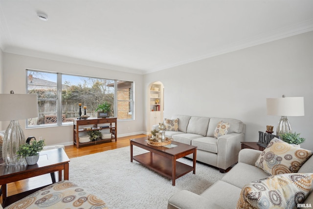 living room with built in features, ornamental molding, and light hardwood / wood-style floors