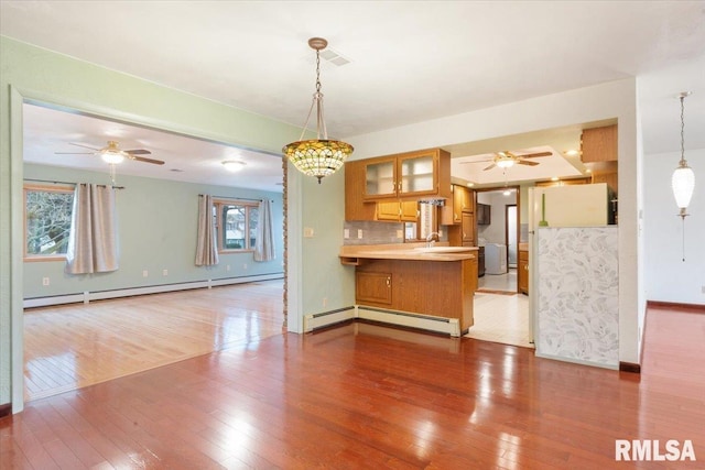 kitchen with kitchen peninsula, tasteful backsplash, fridge, and a baseboard heating unit