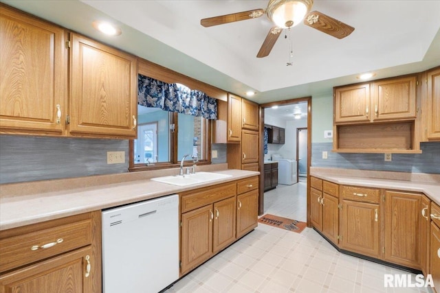 kitchen featuring ceiling fan, sink, tasteful backsplash, white dishwasher, and washer / dryer