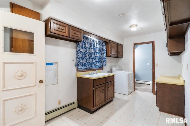 laundry area with baseboard heating, washing machine and dryer, sink, and cabinets