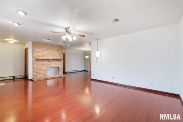 unfurnished living room featuring hardwood / wood-style flooring, a stone fireplace, ceiling fan, and a baseboard heating unit