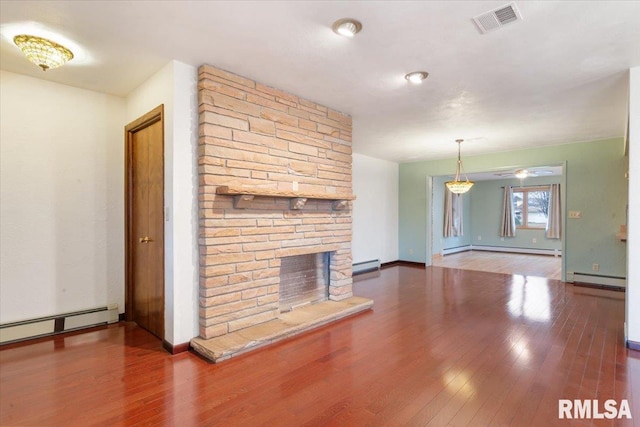 unfurnished living room featuring hardwood / wood-style floors, a stone fireplace, and baseboard heating