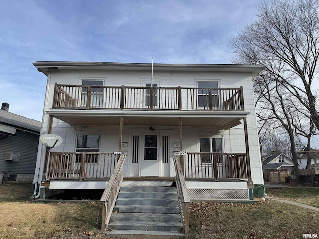 view of front of house with a front yard, covered porch, a balcony, and a wall unit AC