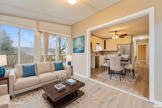 living room with a wealth of natural light, sink, ceiling fan, and light hardwood / wood-style floors