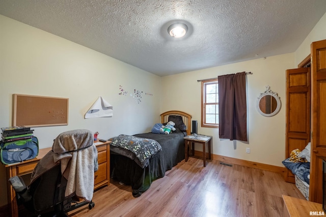 bedroom featuring a textured ceiling and light hardwood / wood-style flooring