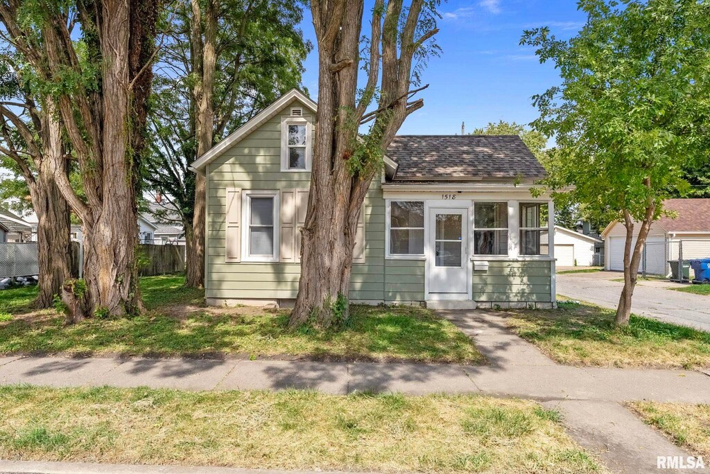 bungalow-style home with roof with shingles and fence