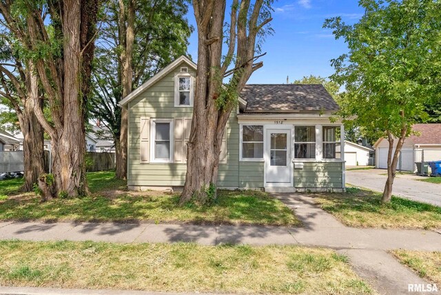 bungalow-style home with roof with shingles and fence