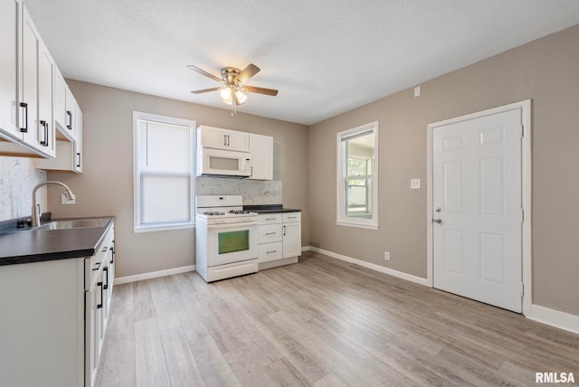 kitchen with white appliances, sink, ceiling fan, light wood-type flooring, and white cabinetry