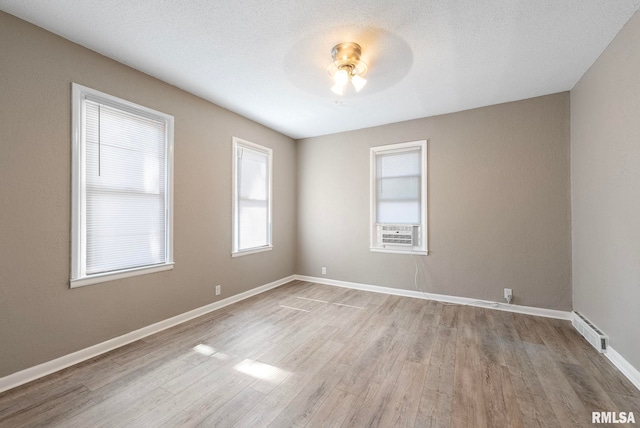 spare room with ceiling fan, cooling unit, light hardwood / wood-style floors, and a textured ceiling