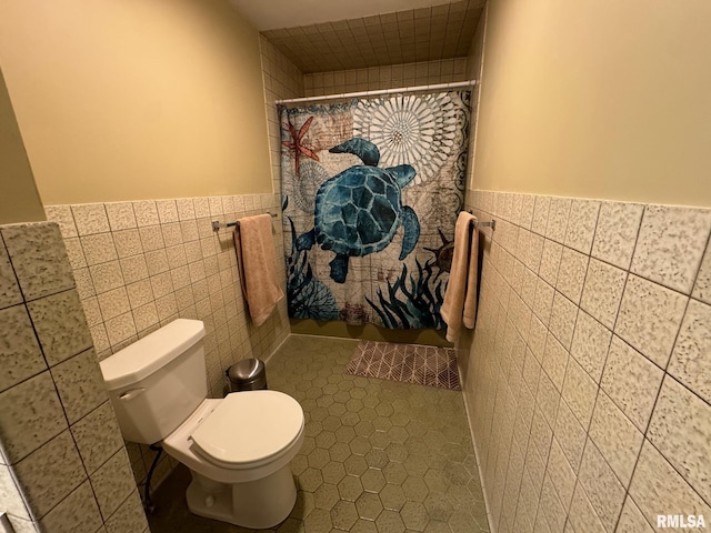 bathroom featuring tile patterned floors, a shower with curtain, tile walls, and toilet